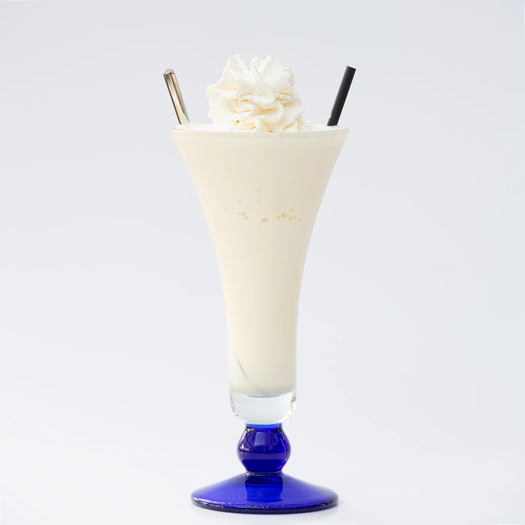 Si vede un bicchere con all'interno un frappè ricoperto da uno spruzzo di panna